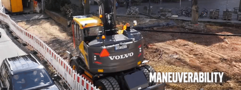 Volvo excavator slewing on a construction jobsite next to a busy road with traffic continuing to move.