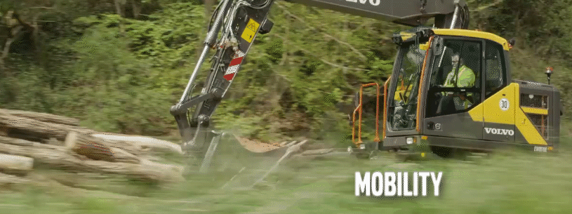 Road contractor driving a Volvo wheeled excavator down a road between construction jobsites.