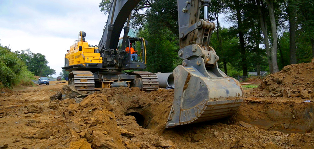 Volvo crawler excavator trenching for laying pipe on a jobsite.