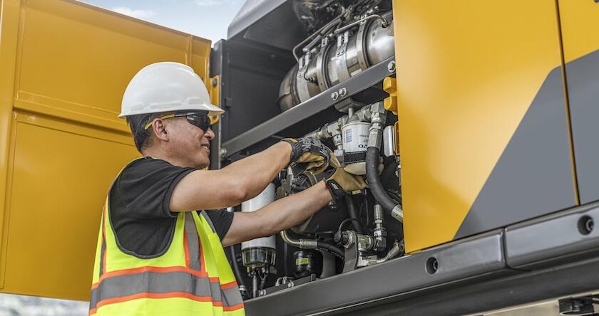 Un technicien d'entretien effectuant l'entretien du moteur d'une pelle hydraulique Volvo.