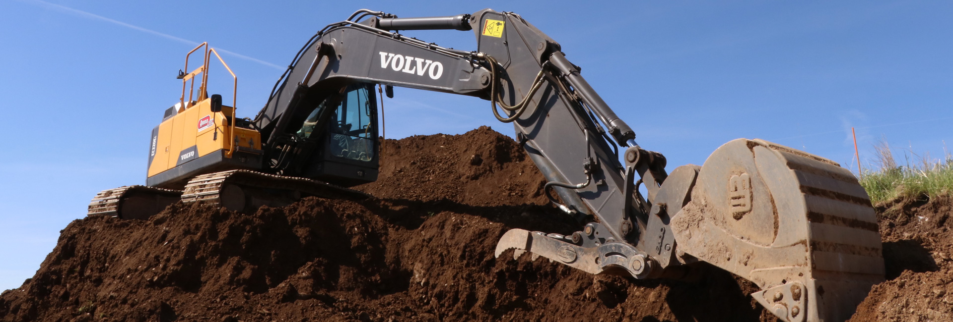 Close up of a Volvo excavator boom and arm digging dirt.