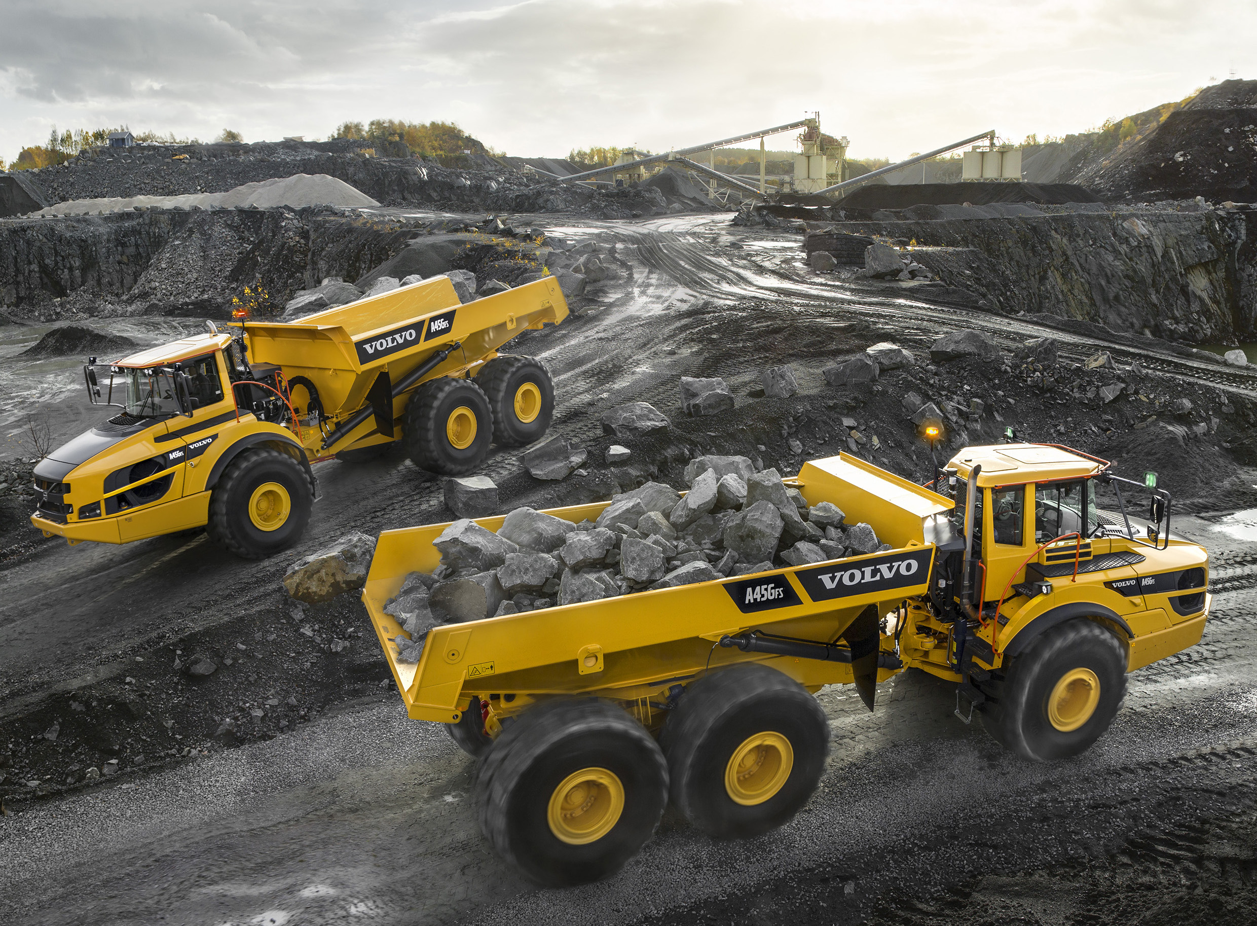 Photo of two Volvo haul trucks hauling rock. 
