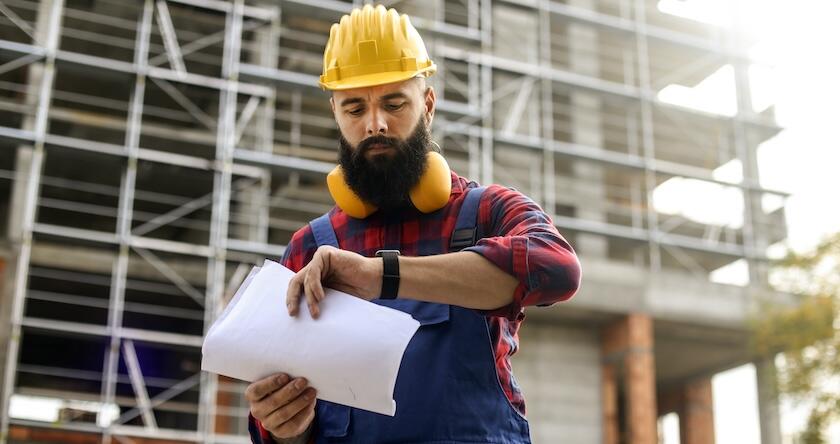 A construction worker on a jobsite looking at his smartwatch.