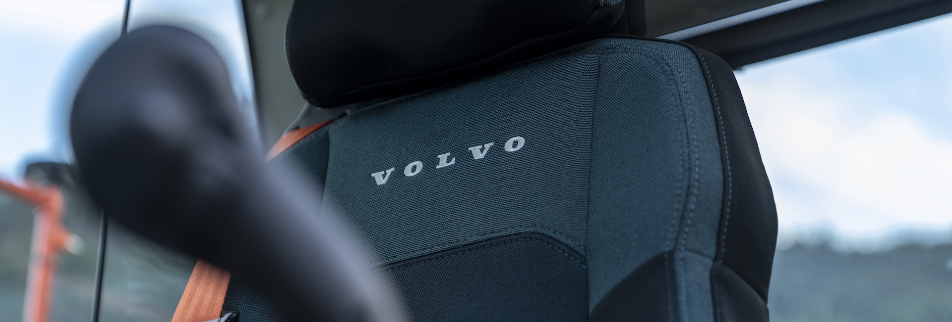 View of the Volvo Deluxe Seat with a joystick control in the foreground in the cab of a new Volvo excavator.