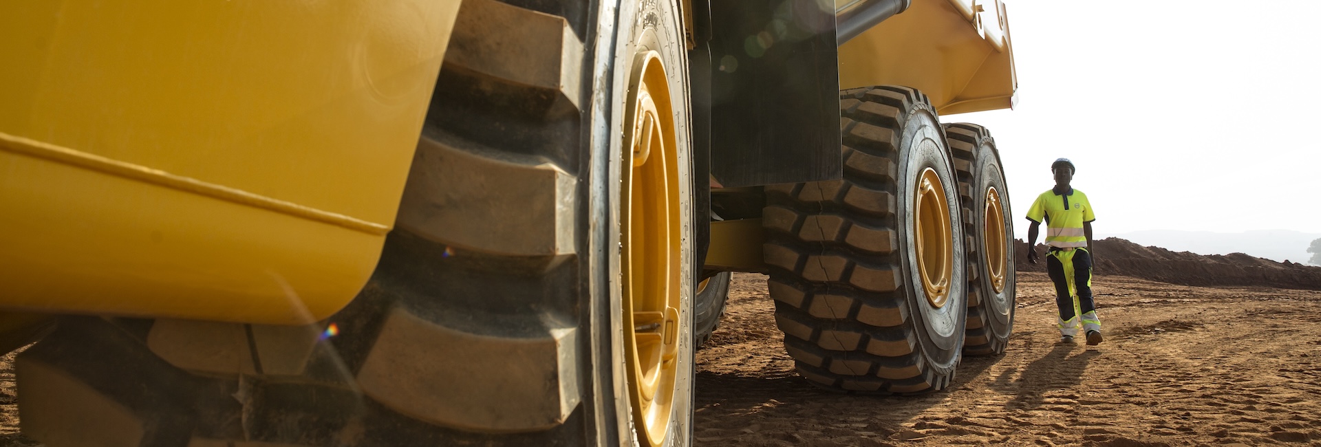 A close-up view of a construction worker looking over an articulated haul truck.