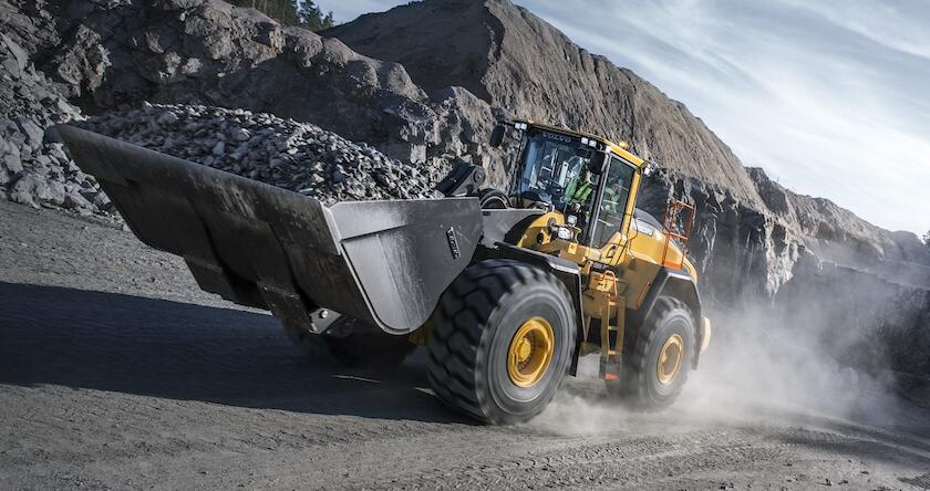 A Volvo L220H wheel loader hauls rock in a quarry.
