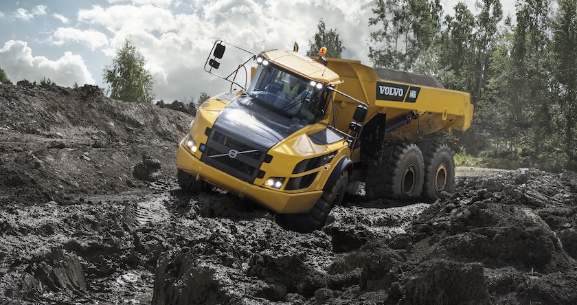 A Volvo articulated truck driving in deep mud.
