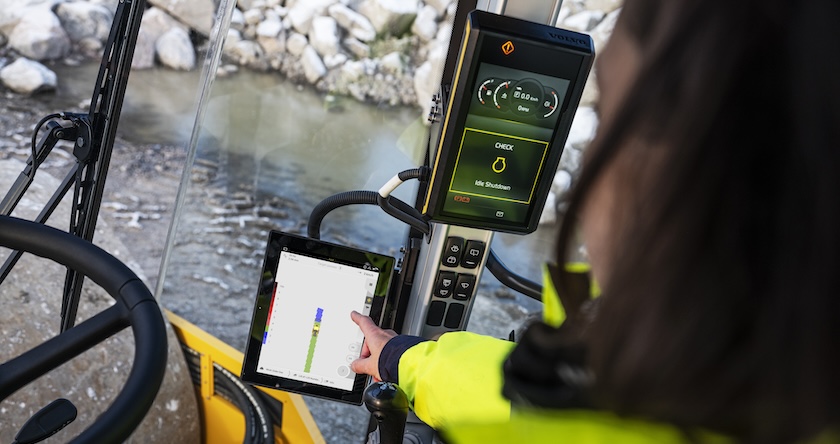 A view from an operator’s perspective out the front of a Volvo soil compactor. The operator is touching and interacting with the Compact Assist for Soil in-cab display.