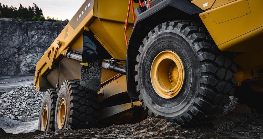 Gros plan sur le groupe motopropulseur d'un nouveau camion articulé Volvo roulant sur un terrain accidenté dans une carrière.