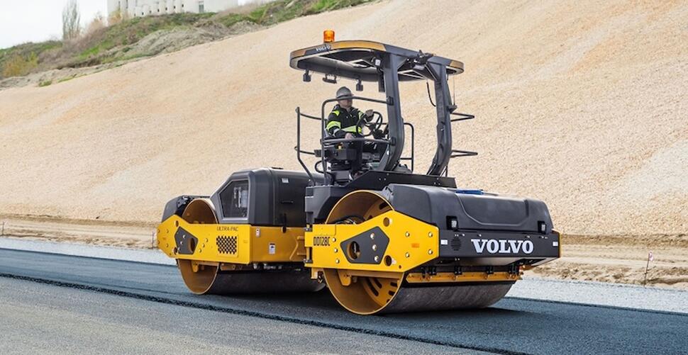 Un compacteur d'asphalte Volvo DD128C roulant sur le tapis d'une nouvelle autoroute.