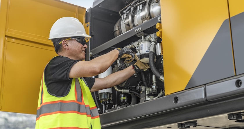 A service tech replacing a Volvo filter on a Volvo excavator.