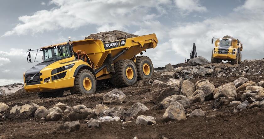 Two Volvo articulated haul trucks hauling rock in a quarry.