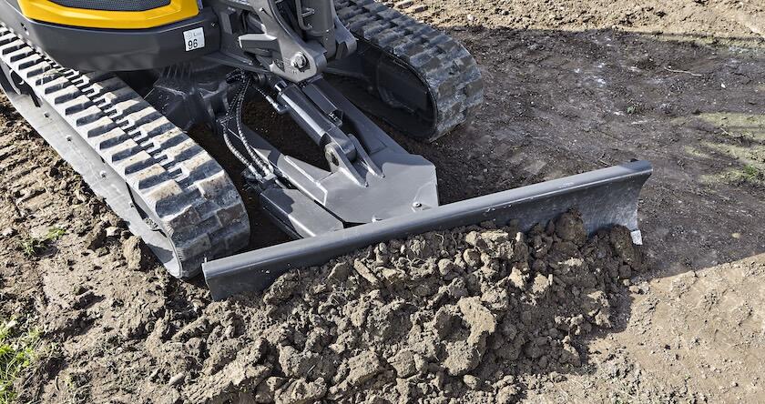 Close-up of an angle blade on a Volvo mini excavator pushing dirt.
