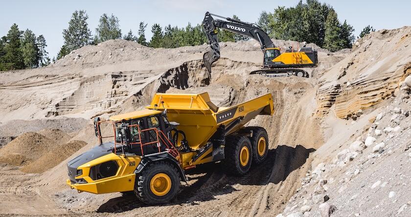 A Volvo articulated dump truck using Downhill Speed Control while being loaded with a Volvo excavator.
