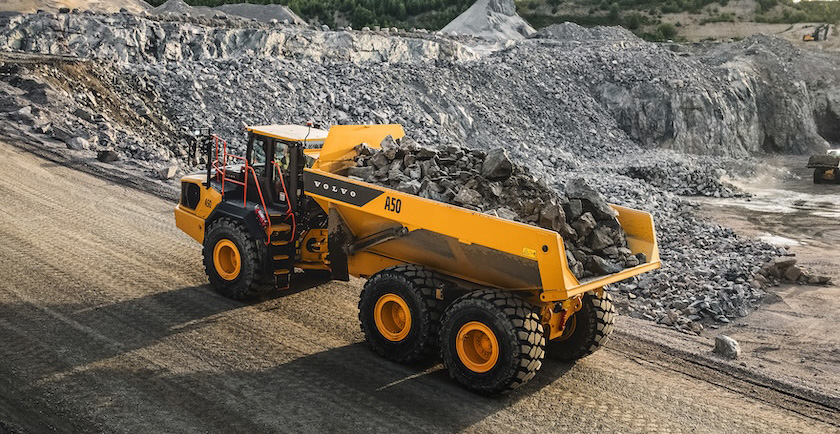 A Volvo A50 articulated hauler carrying rock down a haul road in a quarry.