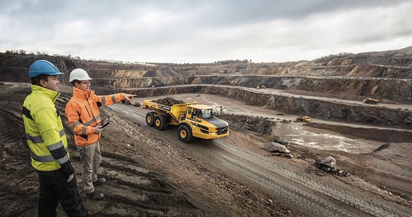 A Volvo Construction Equipment dealer and site manager overlooking a mining site with a Volvo ADT on the haul road.