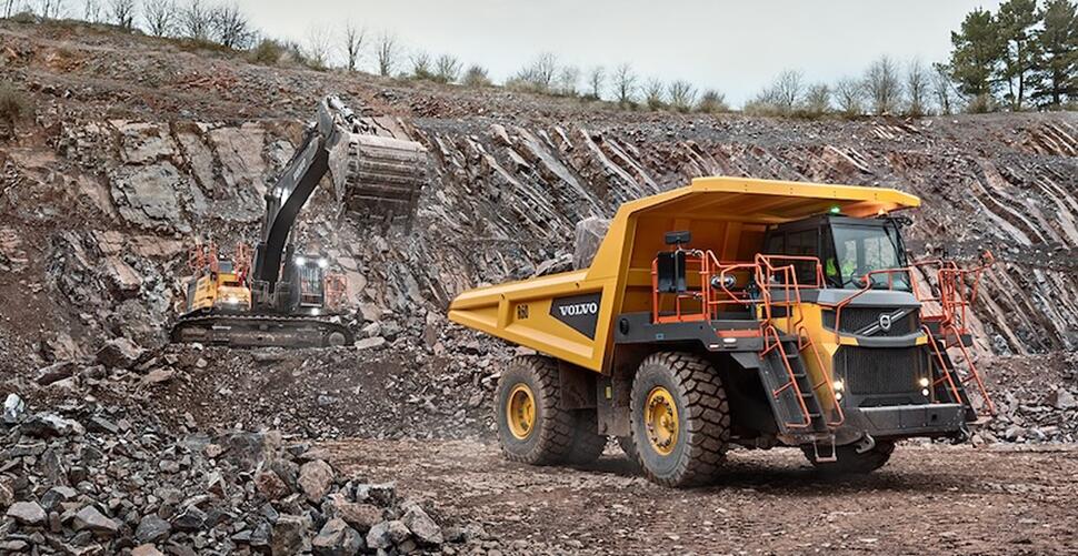 A Volvo excavator loading material into a Volvo R60 mining haul truck in an overburden mining application.