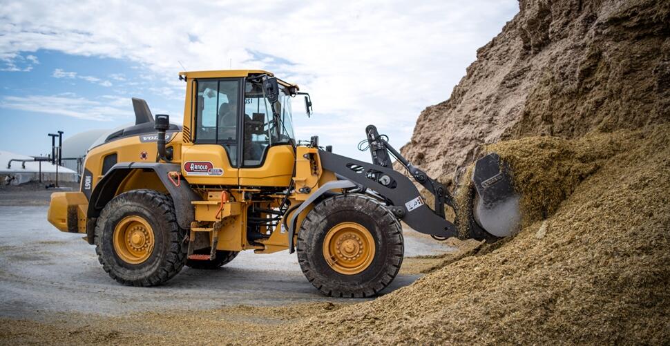 A Volvo L90 wheel loader moves silage at a dairy farm.
