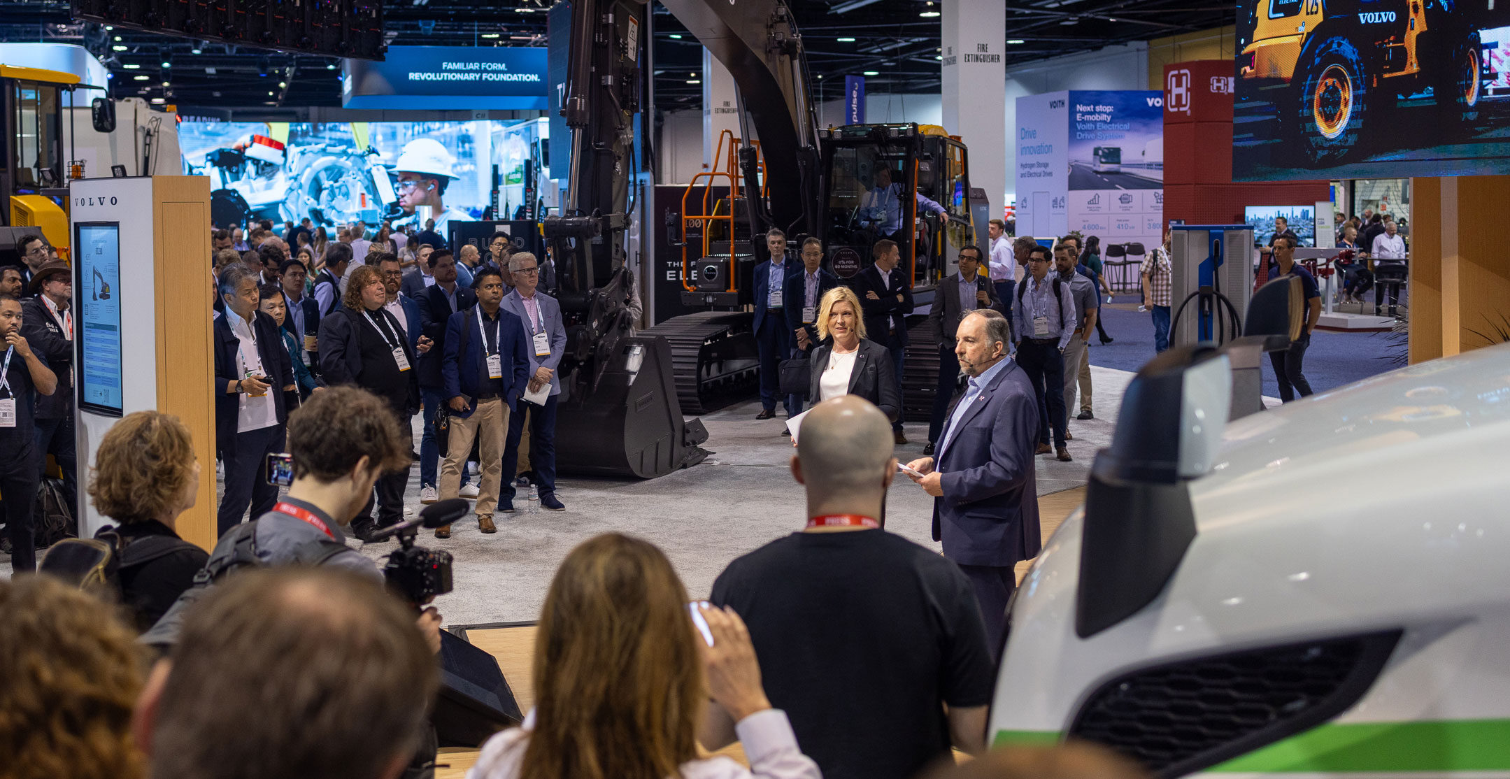 Dr. Ray Gallant shares e-mobility updates next to the EC230 Electric excavator at ACT Expo.