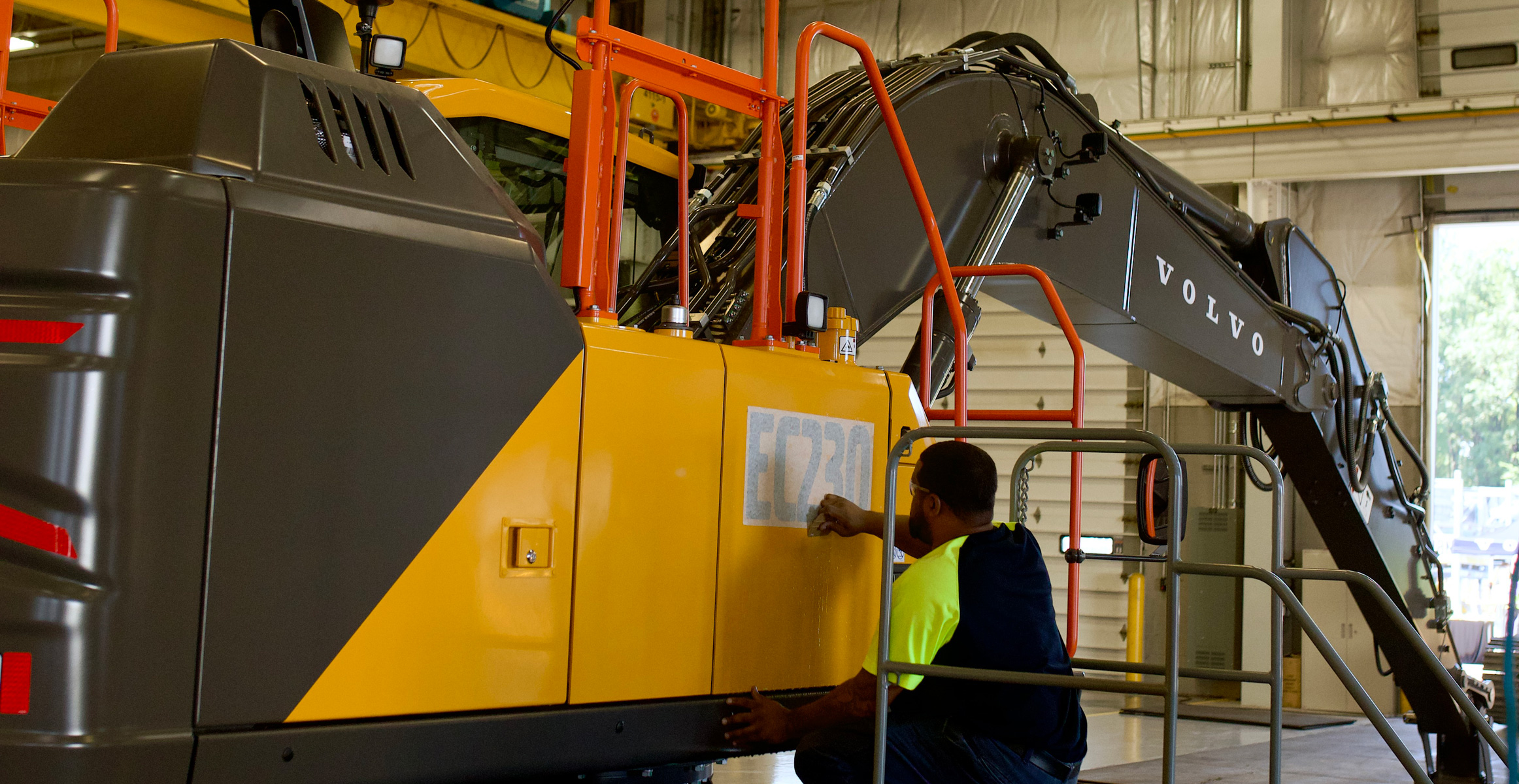 A Volvo CE employee adds a product sticker to an EC230 Excavator on the production line at the Shippensburg facility.