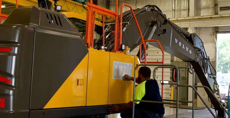 A Volvo CE employee adds a product sticker to an EC230 Excavator on the production line at the Shippensburg facility.