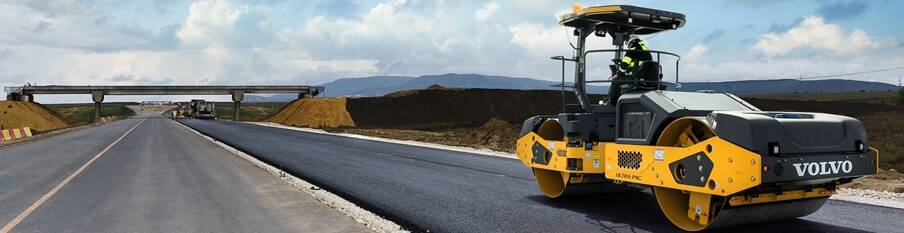 A Volvo DD128C asphalt compactor rolling the mat of a new highway.