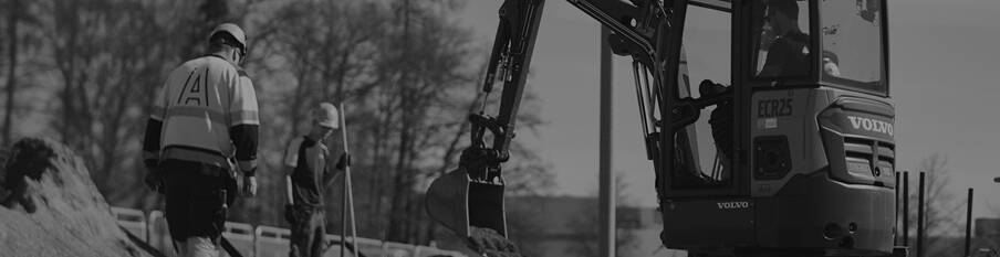 A construction crew works on a job using a Volvo electric excavator. 
