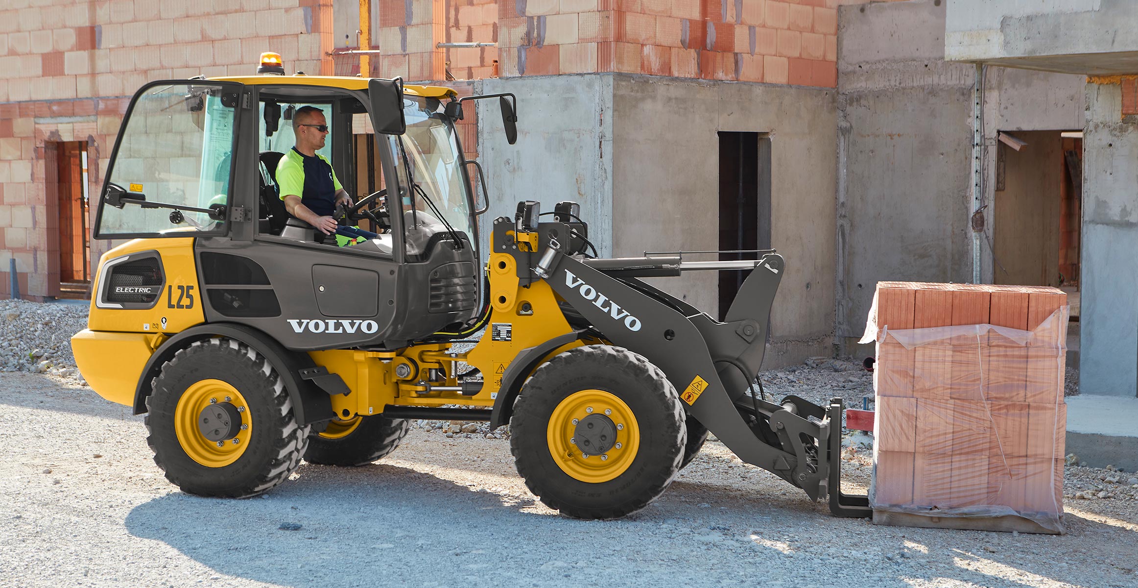 Volvo electric wheel loader lifting a pallet of brick