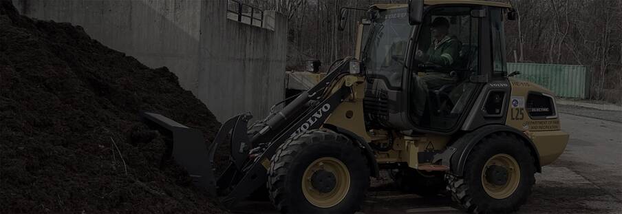 Volvo L25 Electric wheel loader scooping into a pile of dirt.