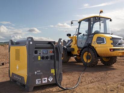A Volvo L25 electric wheel loader charging on a portable charger on a remote jobsite.