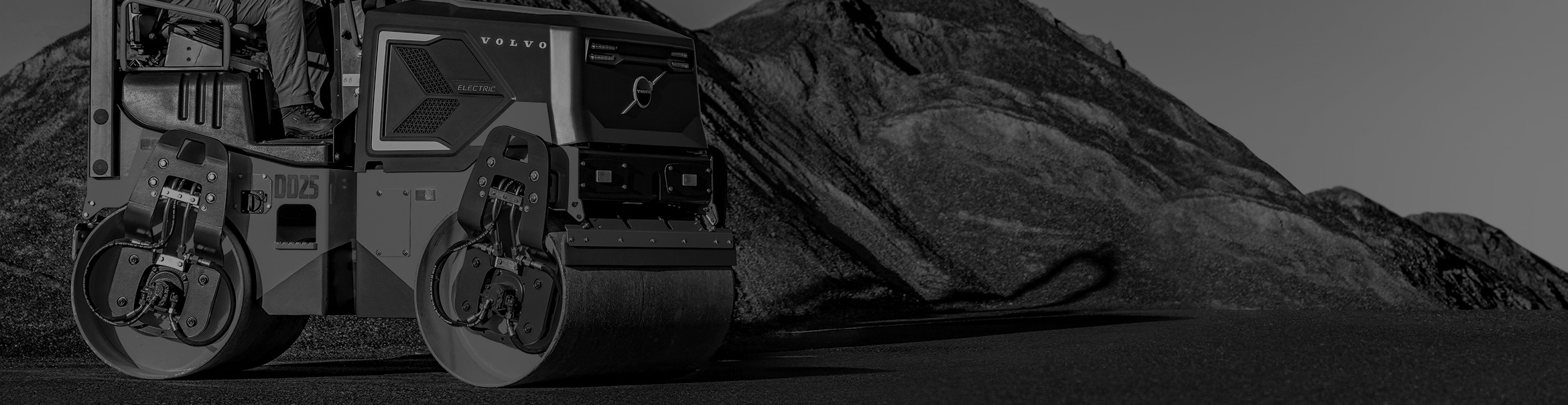 The Volvo DD25 Electric compactor sitting by material used in road construction projects.