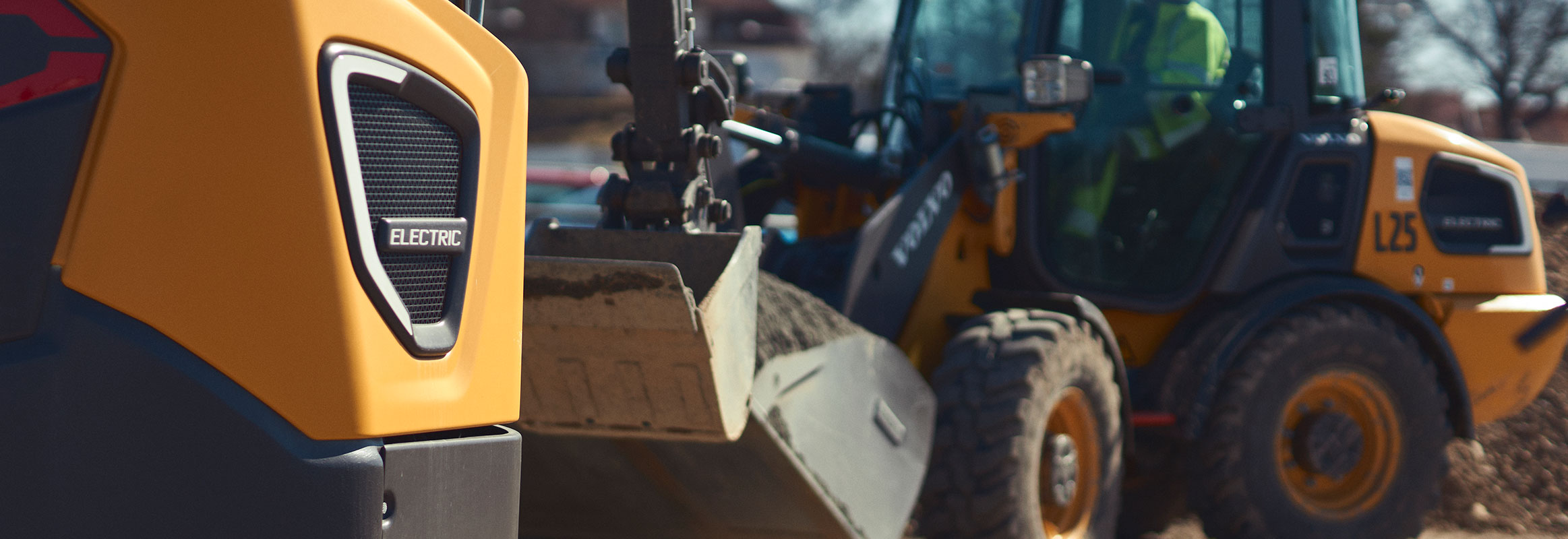  Volvo electric machines — an electric excavator and wheel loader — move earth on a construction jobsite.