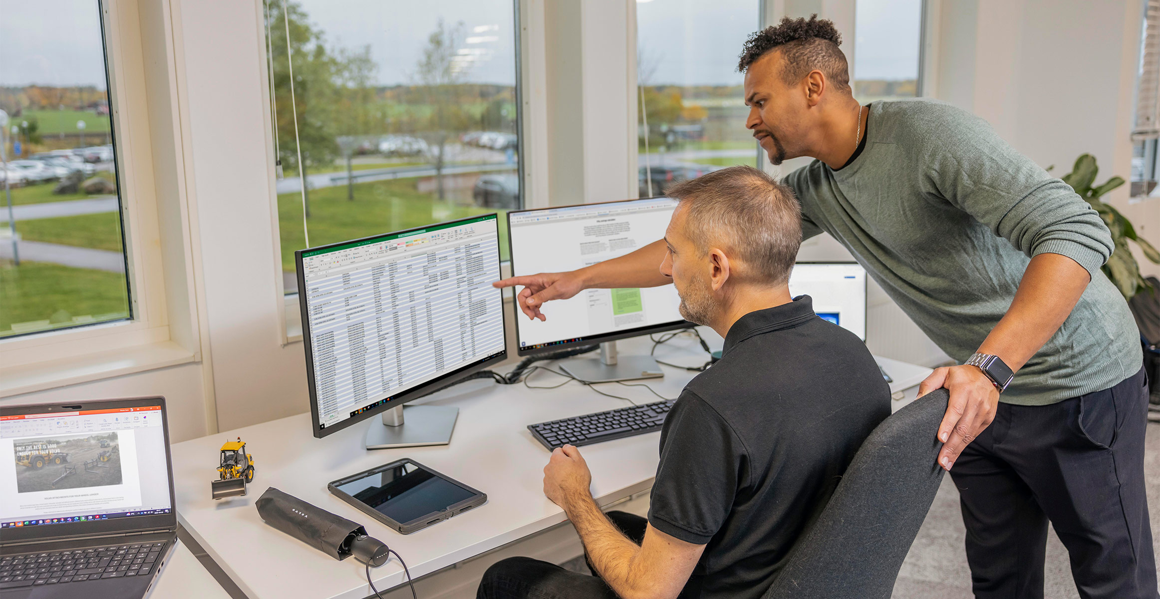 Two Volvo Uptime Center employees reviewing ActiveCare Direct data for a customer on a computer.