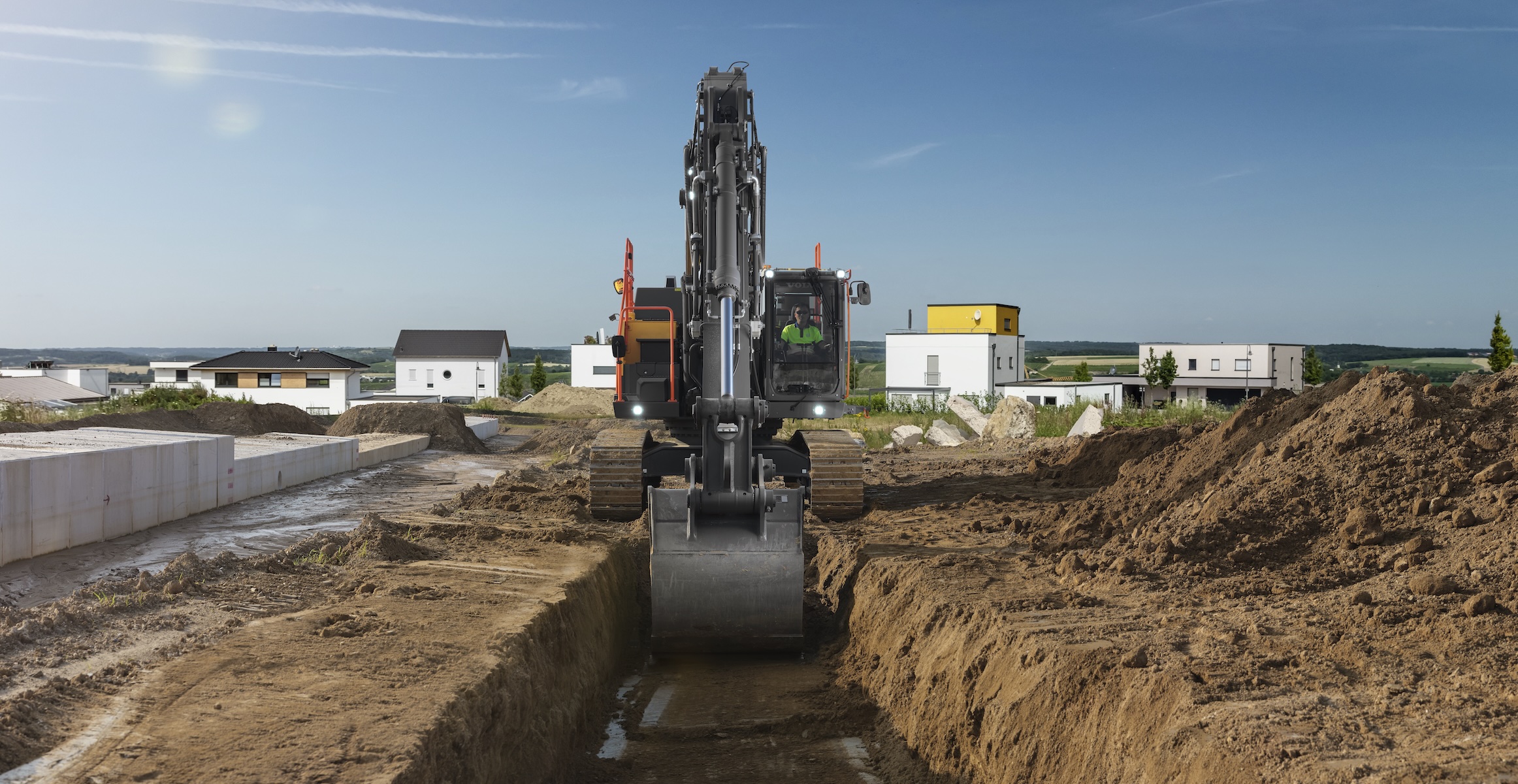 ​A Volvo tracked excavator trenching on a construction site. 