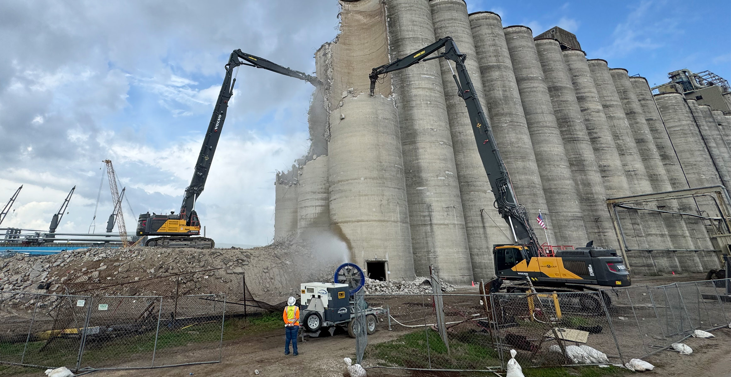 Two Volvo high-reach demolition excavators taking down silos.