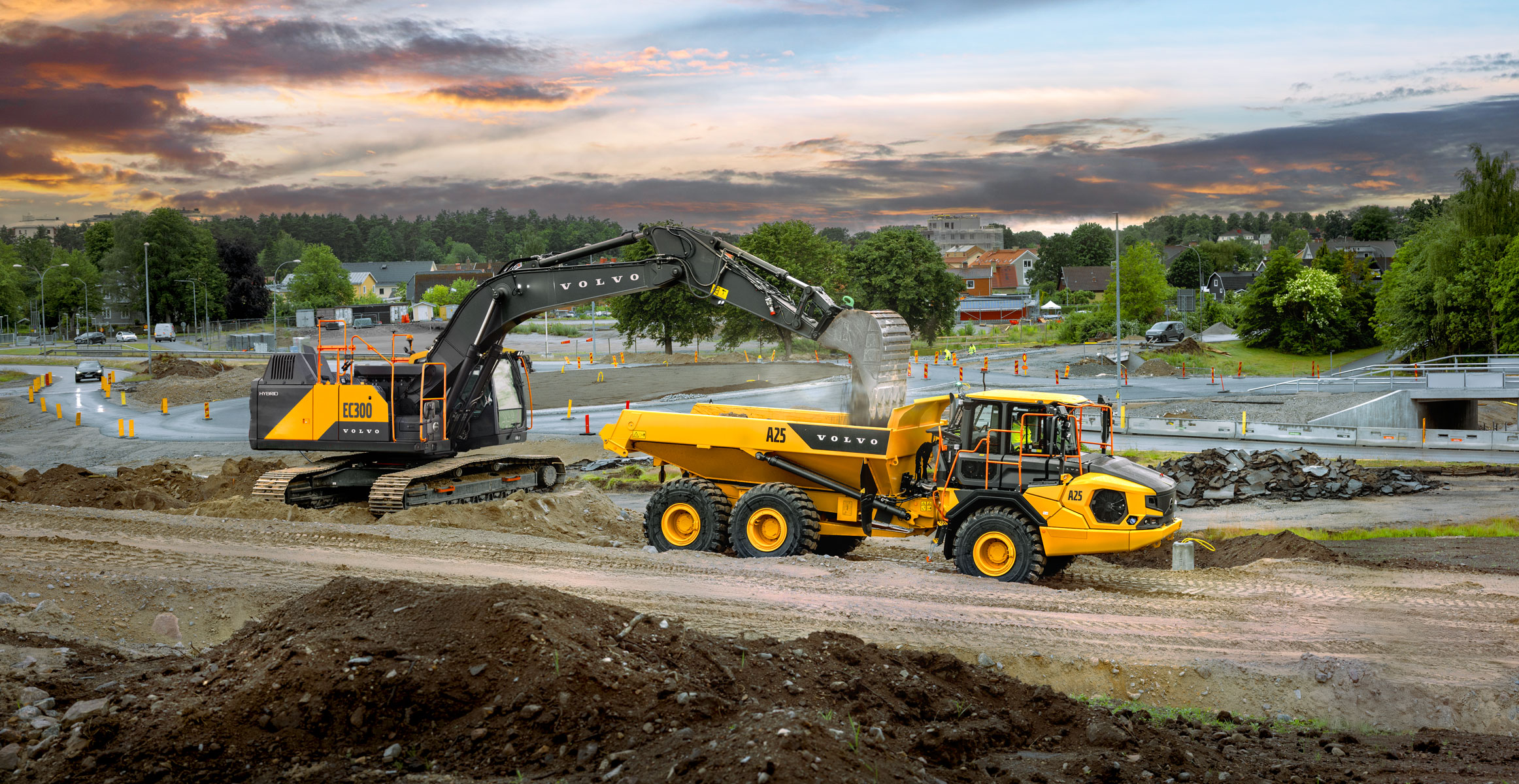A Volvo EC300 excavator loading dirt into a Volvo A25 articulated dump truck on a construction jobsite.