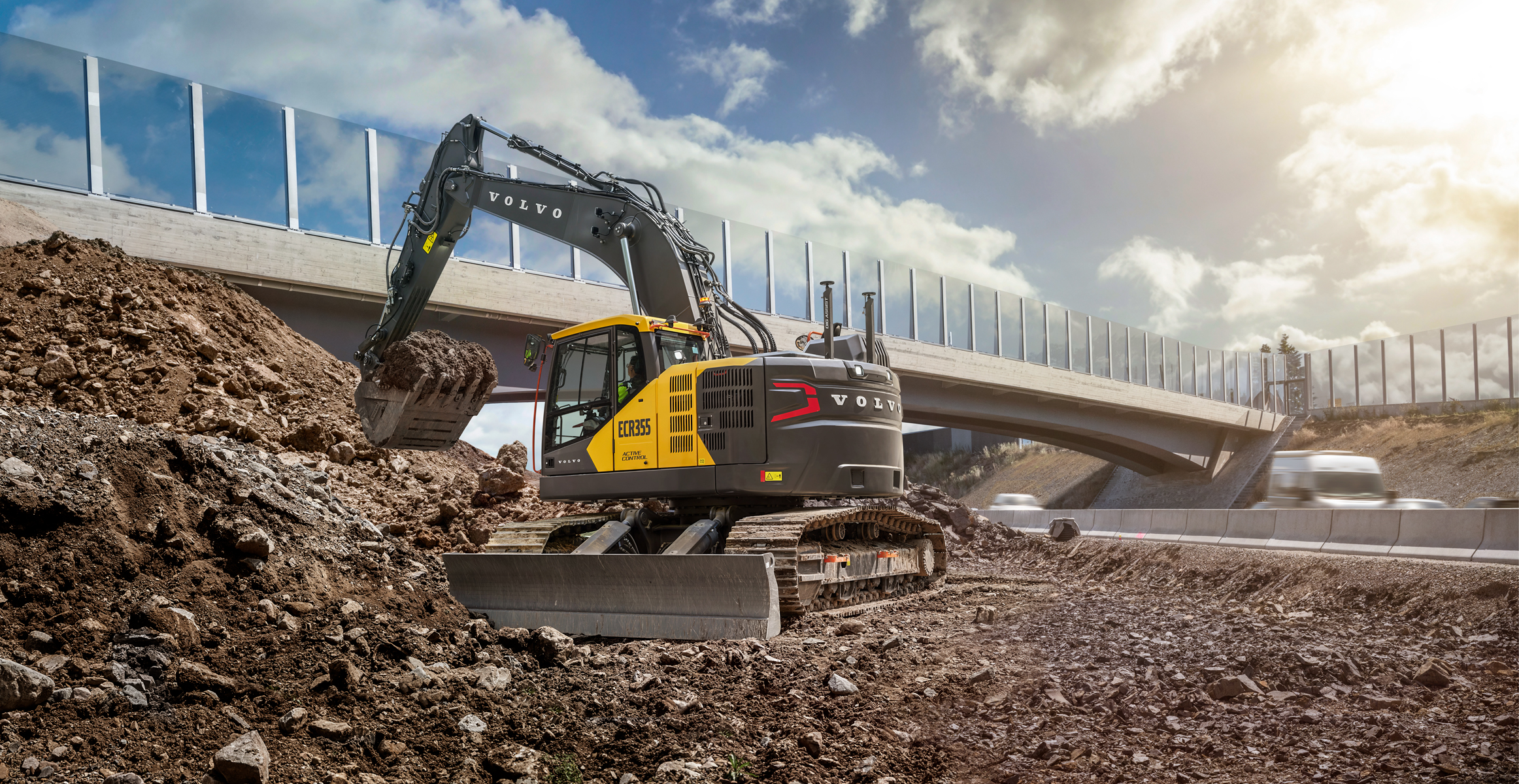 A Volvo ECR355 excavator moving dirt in highway construction.