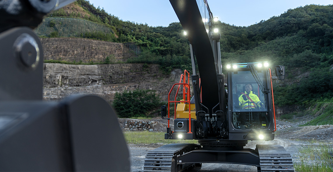 A Volvo EC230 excavator with the safety lights illuminated toward the viewer. 