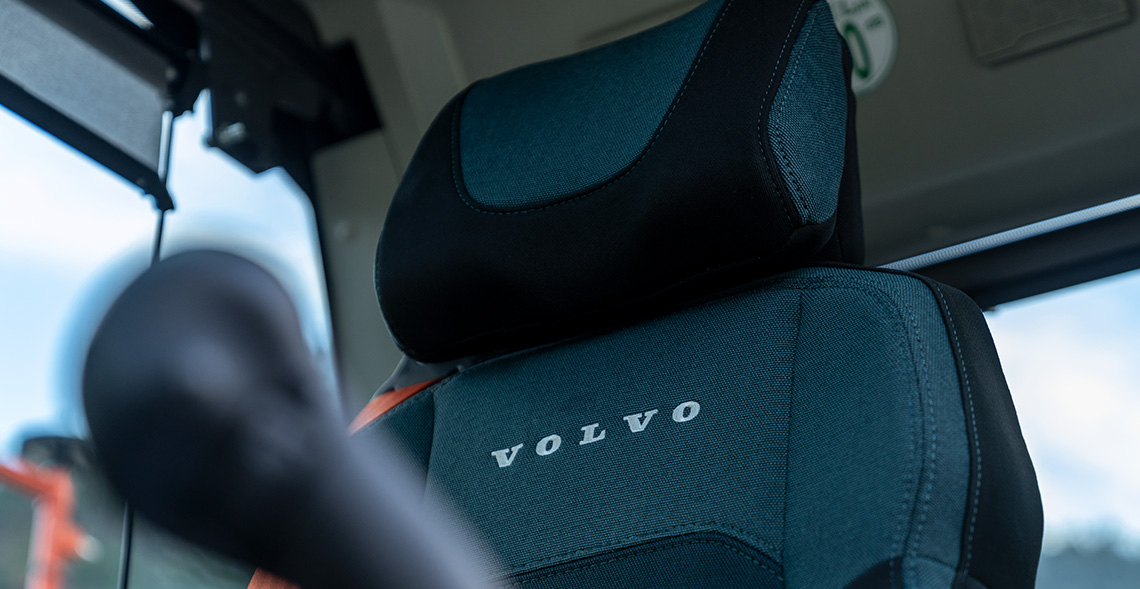 A view of the deluxe seat in a Volvo EC230 tracked excavator, with the joystick blurred in the foreground. 