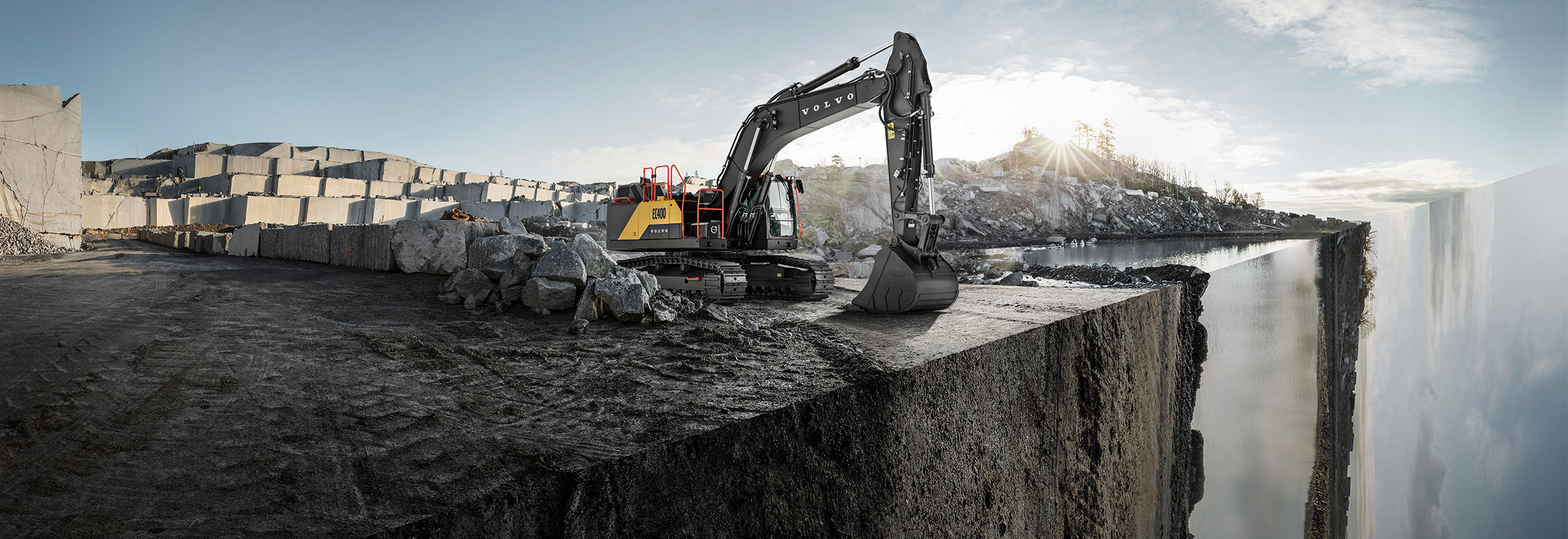A Volvo excavator at the edge of a jobsite with a diagonal portion of the site dropping off vertically.