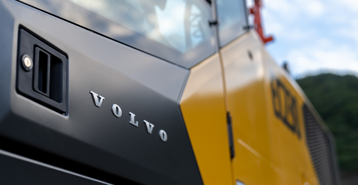 A close-up shot of the Volvo logo on a cab door of a Volvo EC230 excavator.