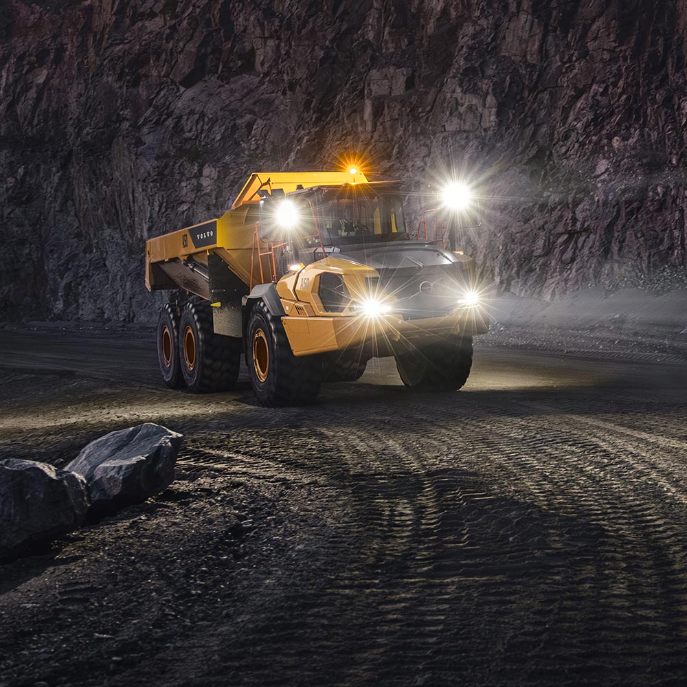 A Volvo ADT using the headlines on a haul road at night.