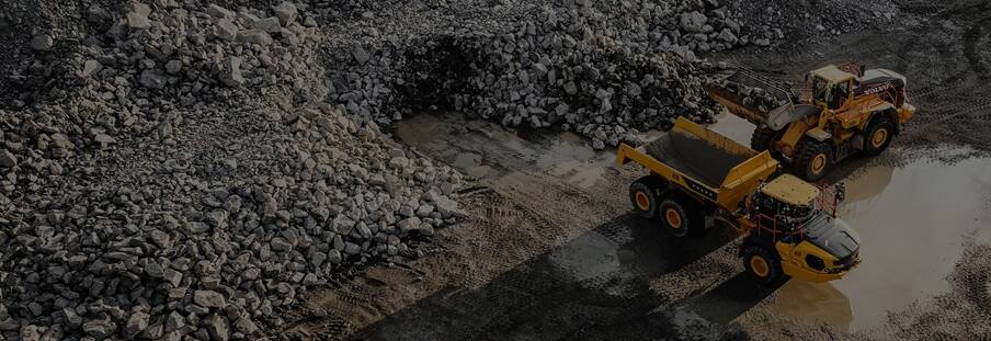 A Volvo wheel loader loading a Volvo articulated haul truck in a quarry.