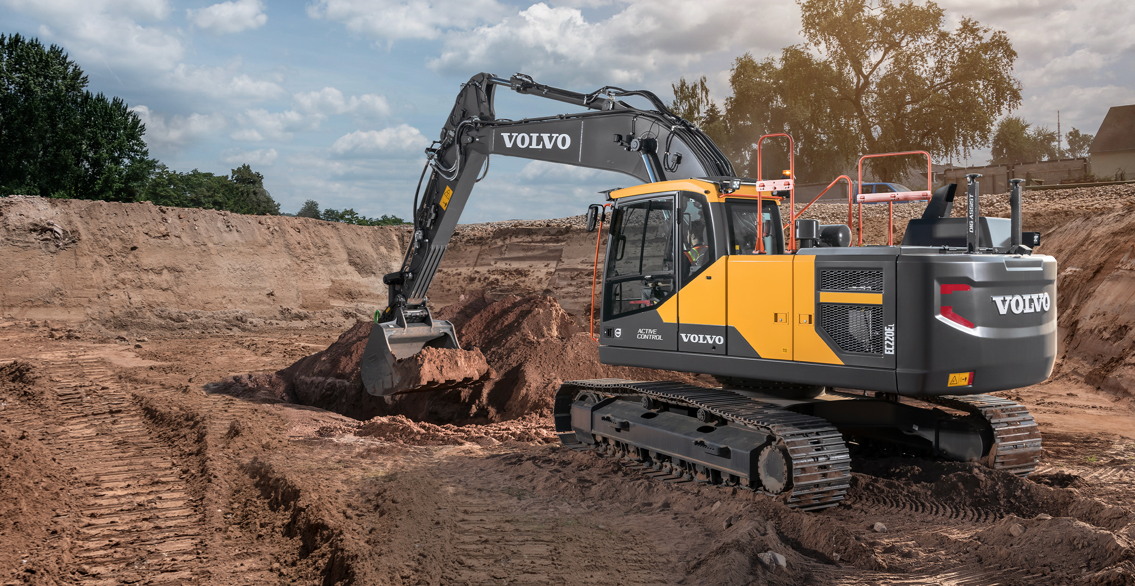 A Volvo excavator digging dirt during the site prep phase on a construction jobsite.