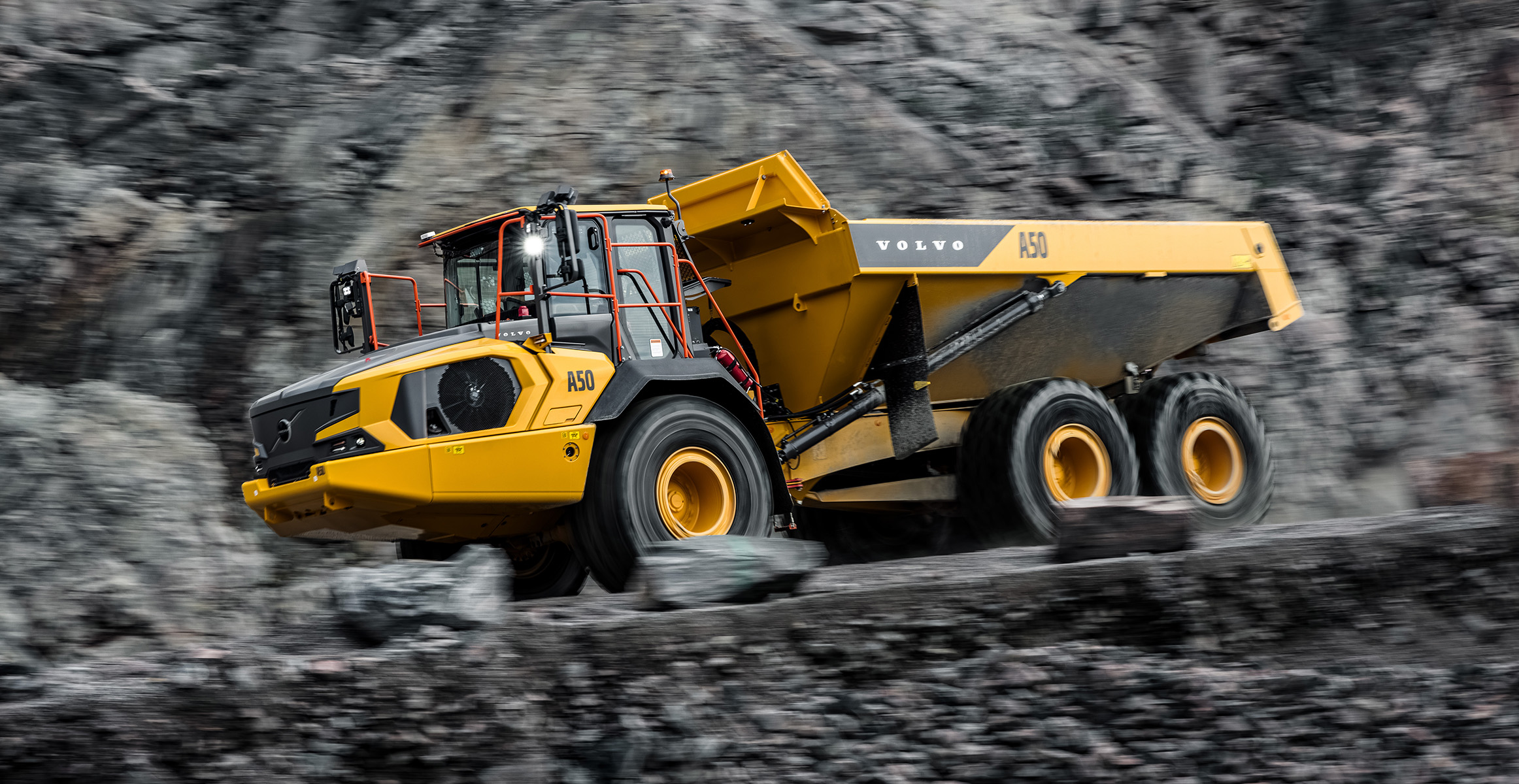 A Volvo A50 articulated dump truck driving on a haul road in a quarry. 