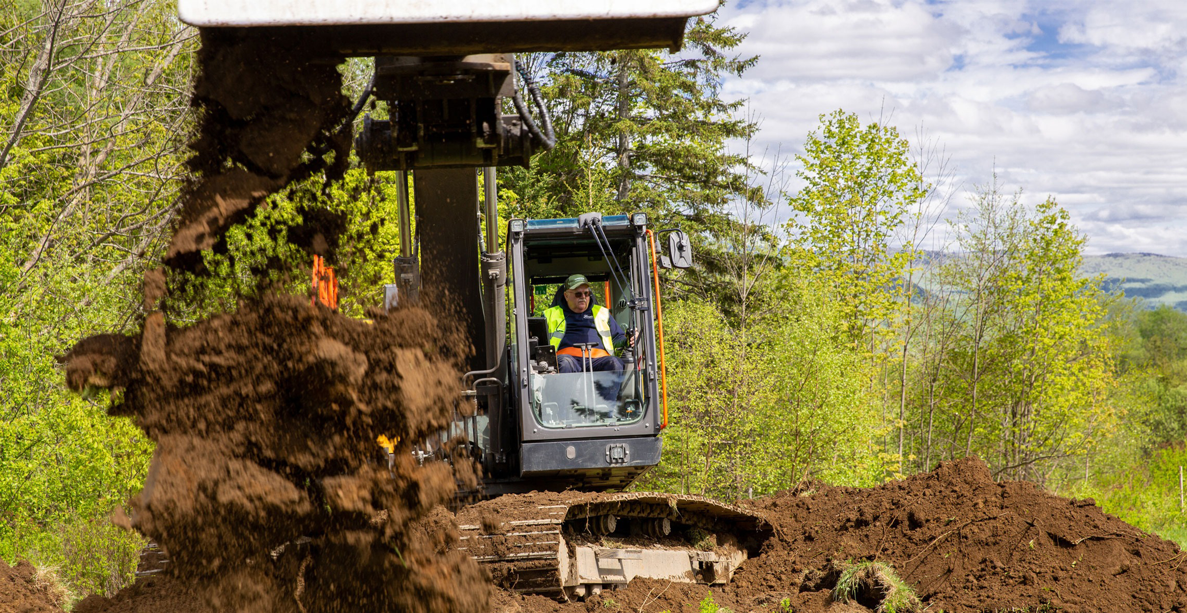 An operator dumping dirt with a Volvo excavator in a site prep application.