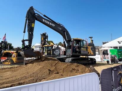 A Utility Expo attendee operating a midsize Volvo electric excavator.