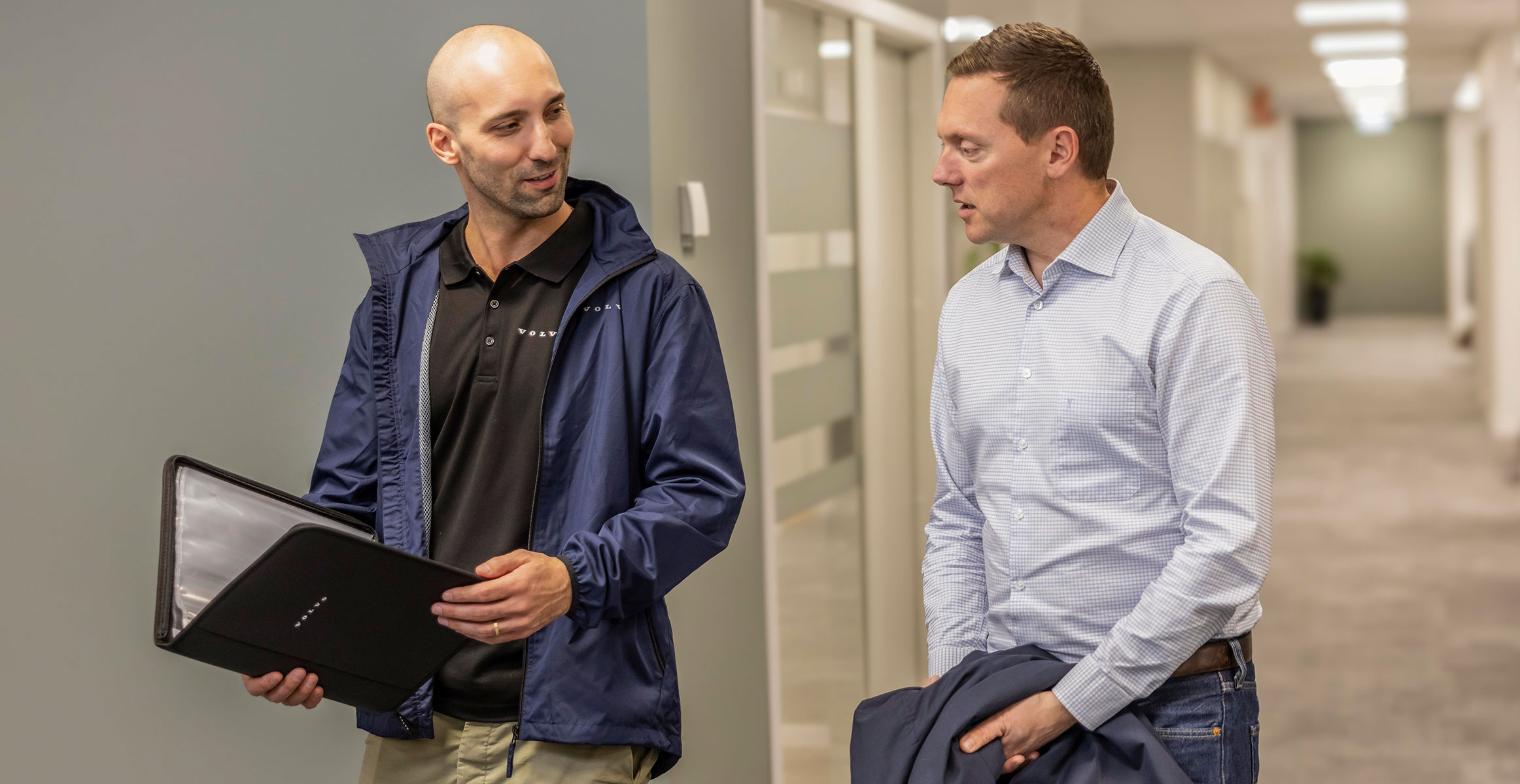 Two men at an office building walking down a hall and talking about construction equipment financing.