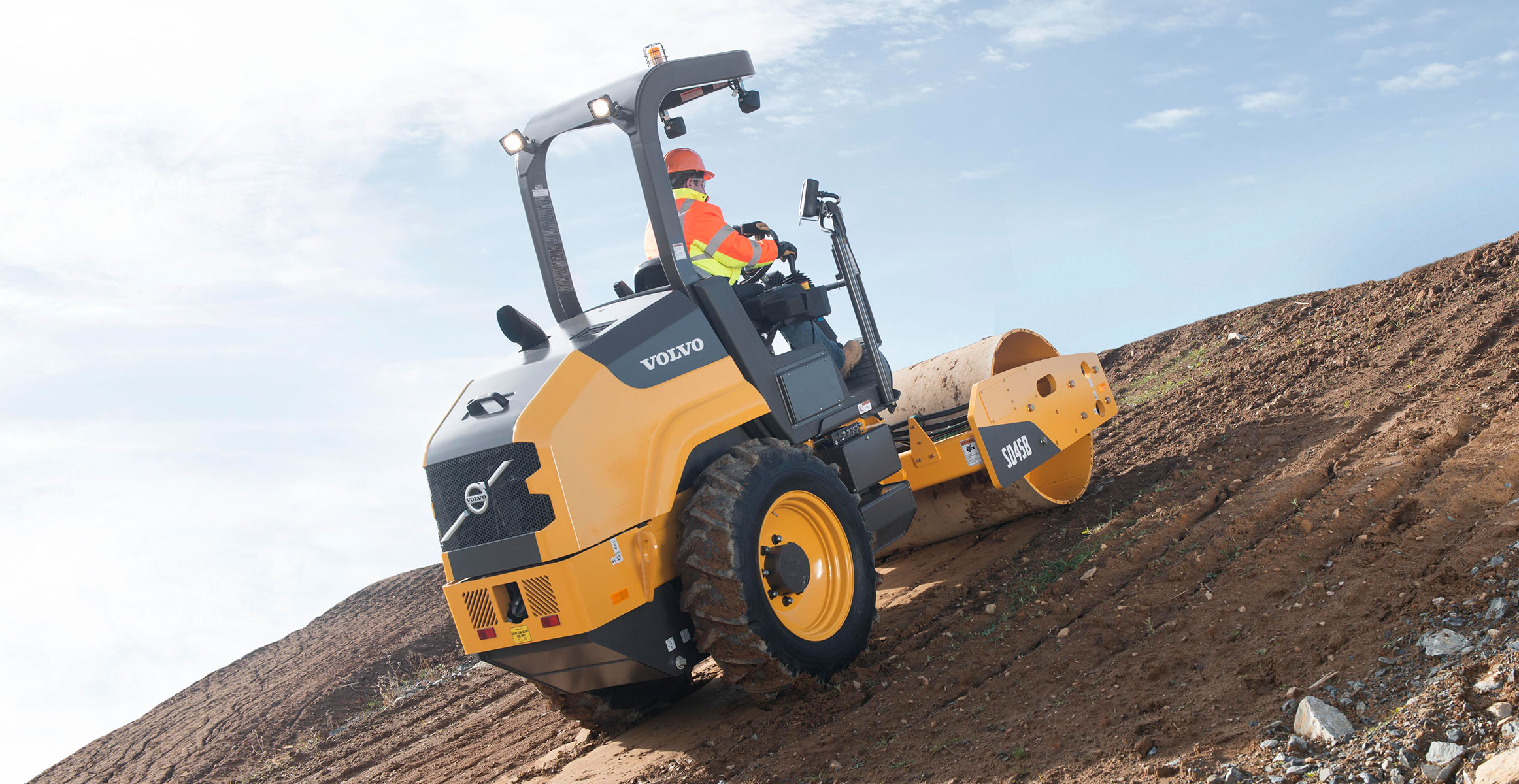 A Volvo soil compactor compacting dirt on an upslope.