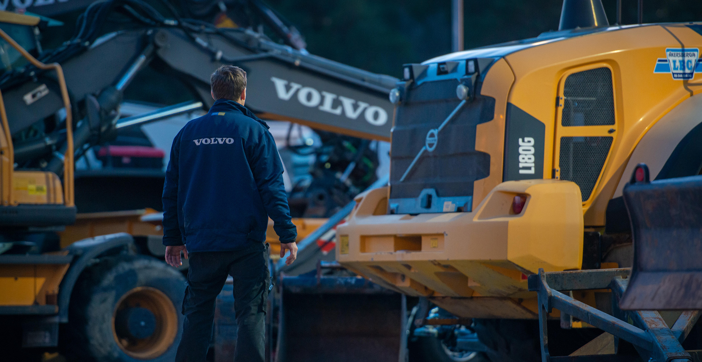 A service technician looking at Volvo construction equipment in a shop.